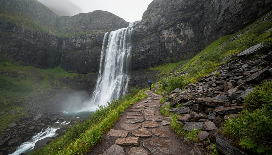 Third Vault Falls cascading into a rocky ravine with a hiker on a nearby trail at Gros Morne National Park